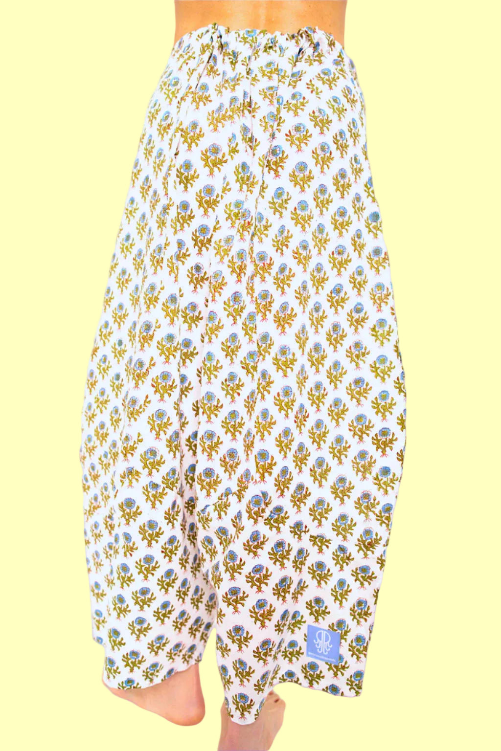 A pair of white pants with a traditional Indian floral design, featuring a drawstring waistband.