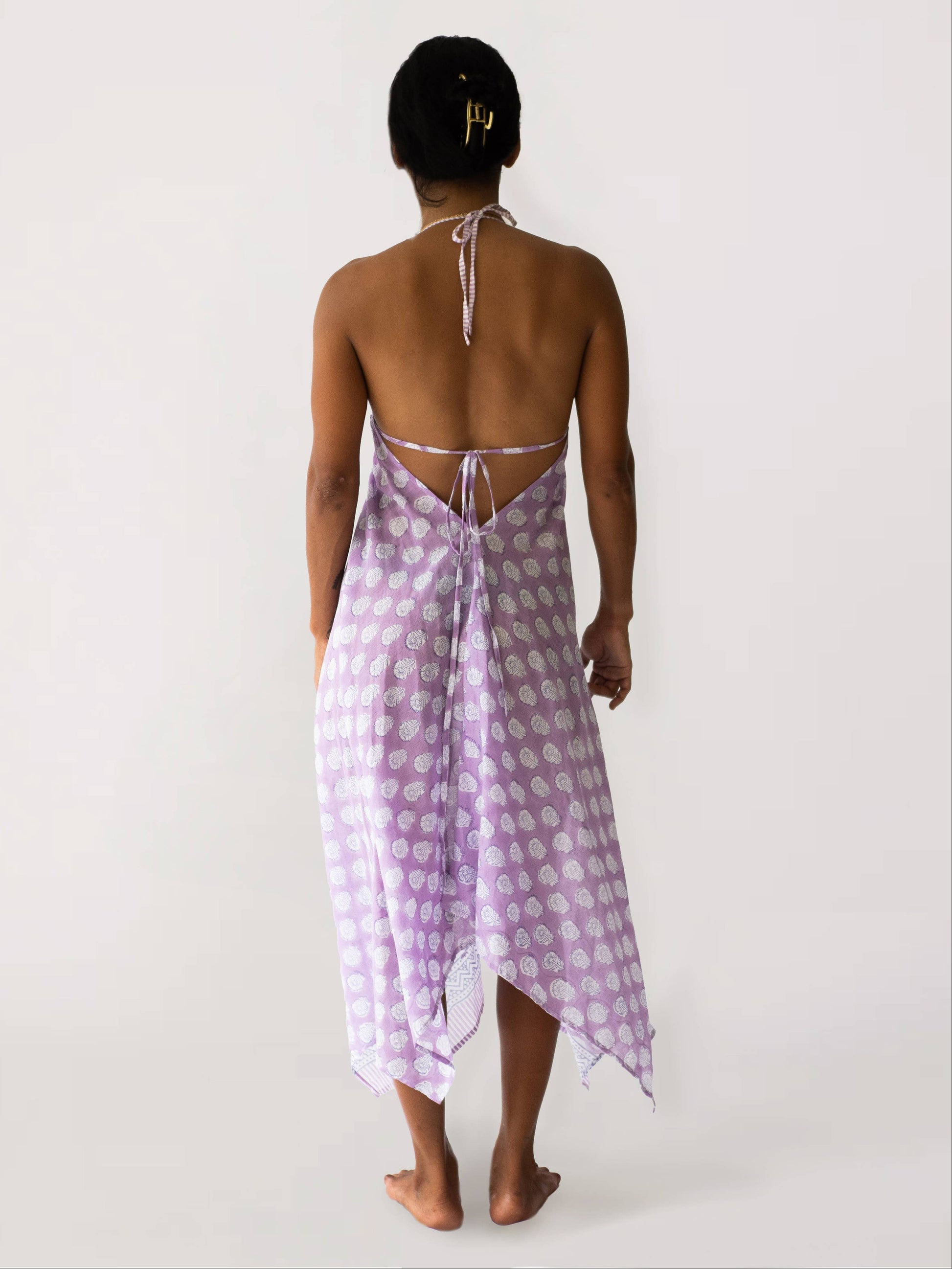 Woman wearing a purple patterned dress with a white background