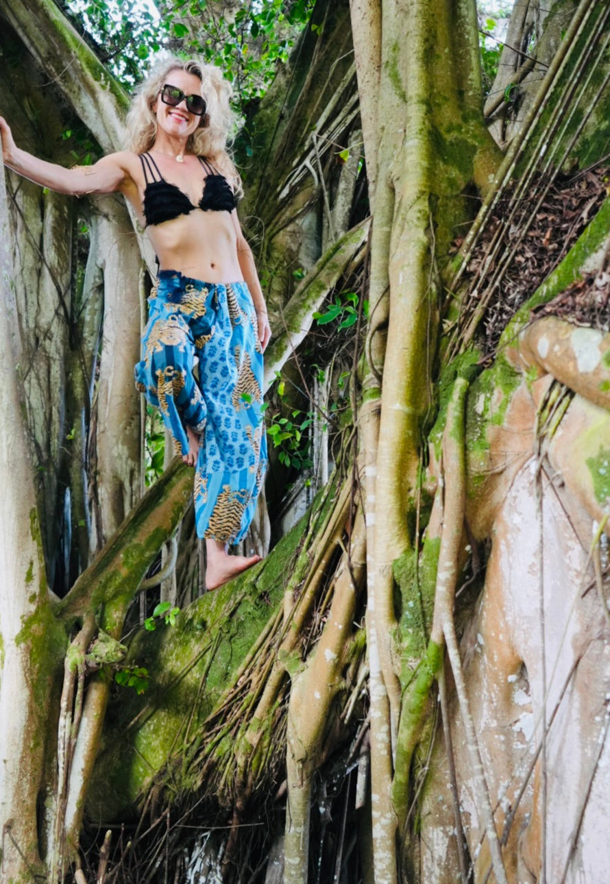 Woman standing among large tree trunks with a forest background