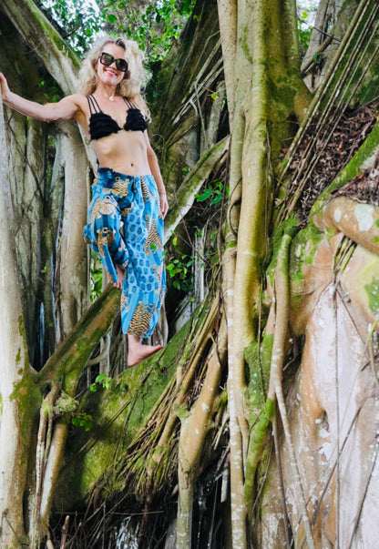 Woman standing among large tree trunks with a forest background