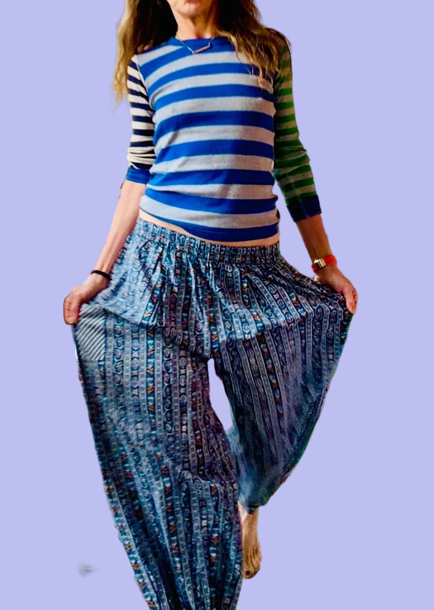 Person wearing a blue and white striped shirt and denim pants in a cluttered room.
