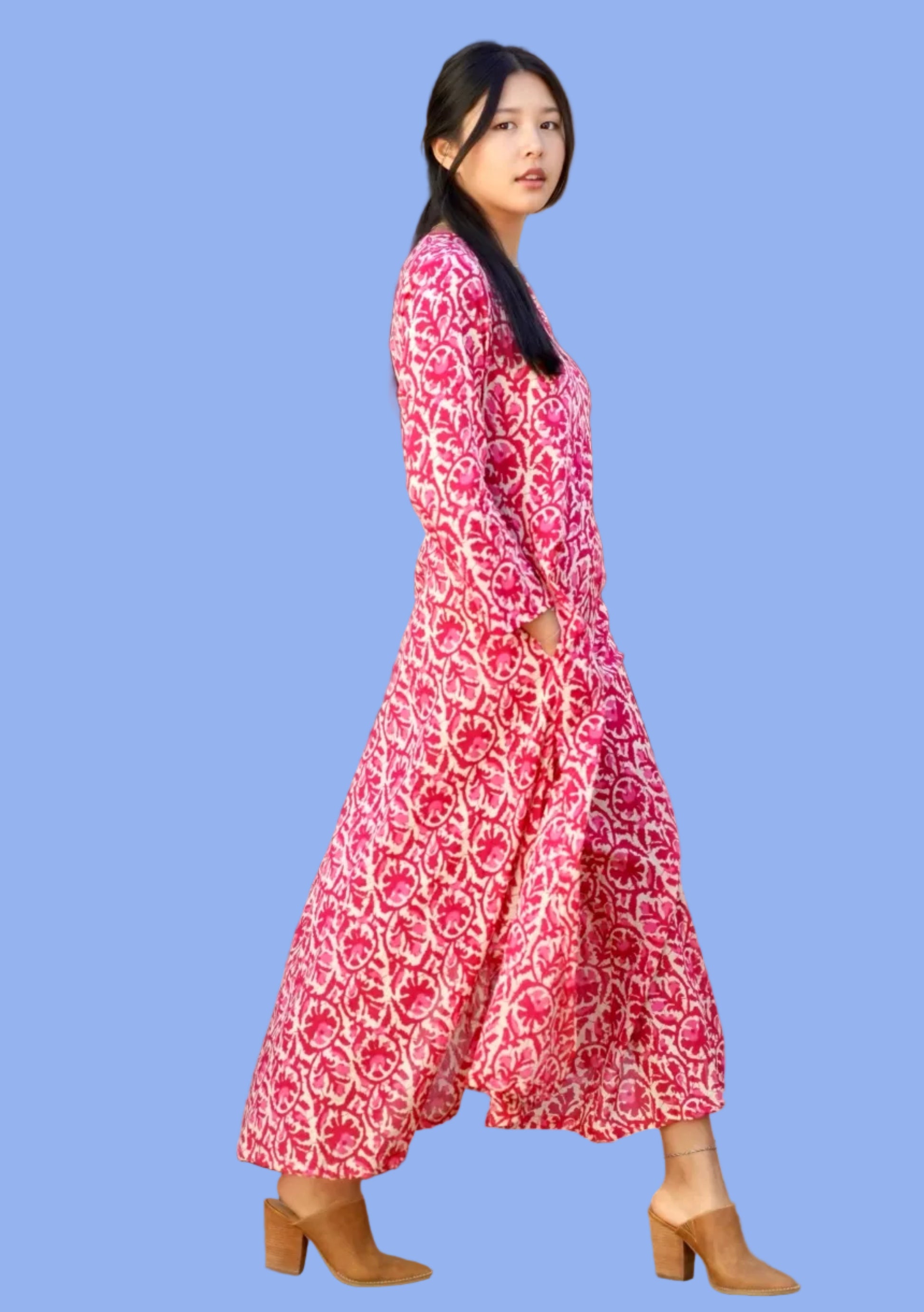 Woman in a red patterned dress standing in front of a door.