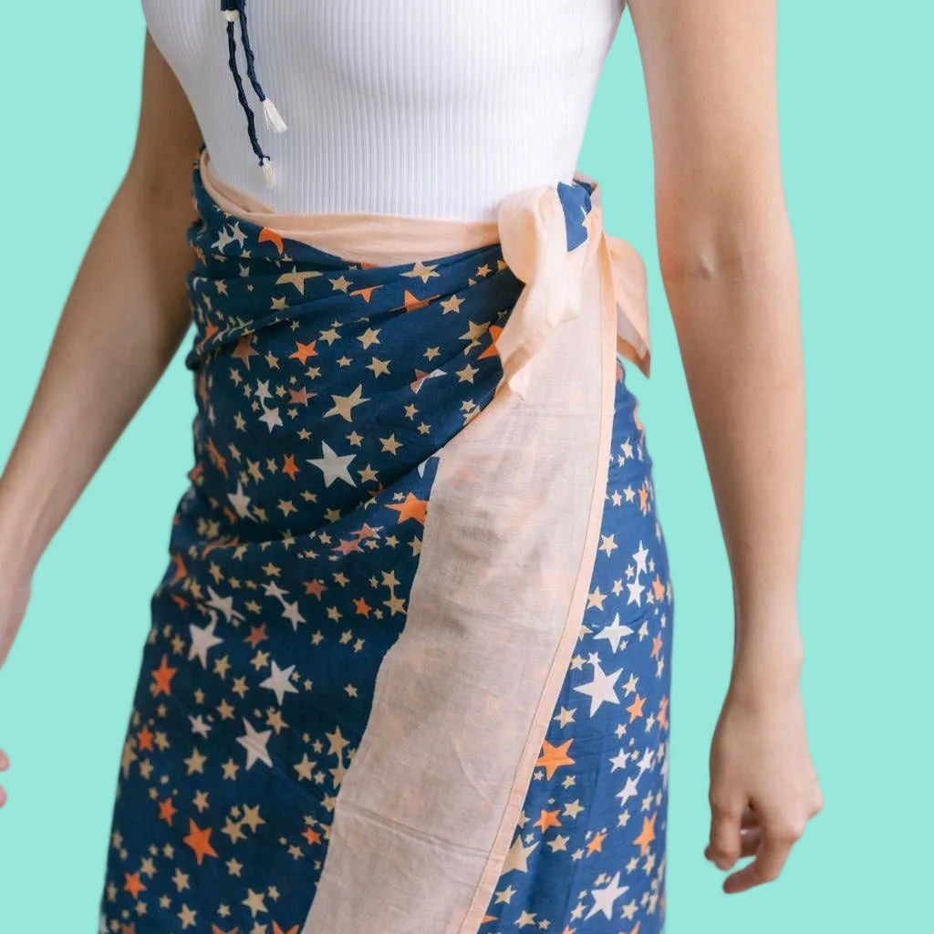 Person wearing a blue star-patterned skirt with a white top on a light background