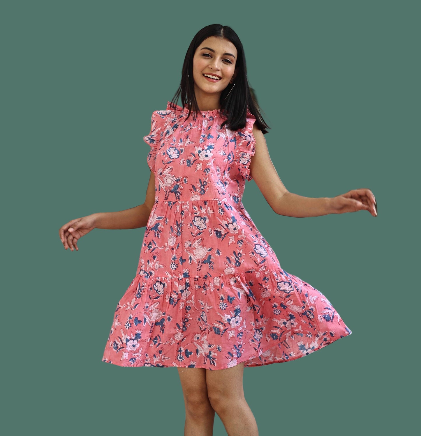 Woman in a pink floral dress standing in front of a white door with glass panels.